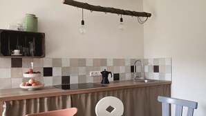 Une cuisine avec un plan de travail en bois, un évier, une bouilloire et une chaise.