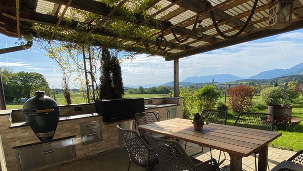 Eine Außenpatio mit Grill, Sitzgelegenheit und Blick auf die Landschaft.