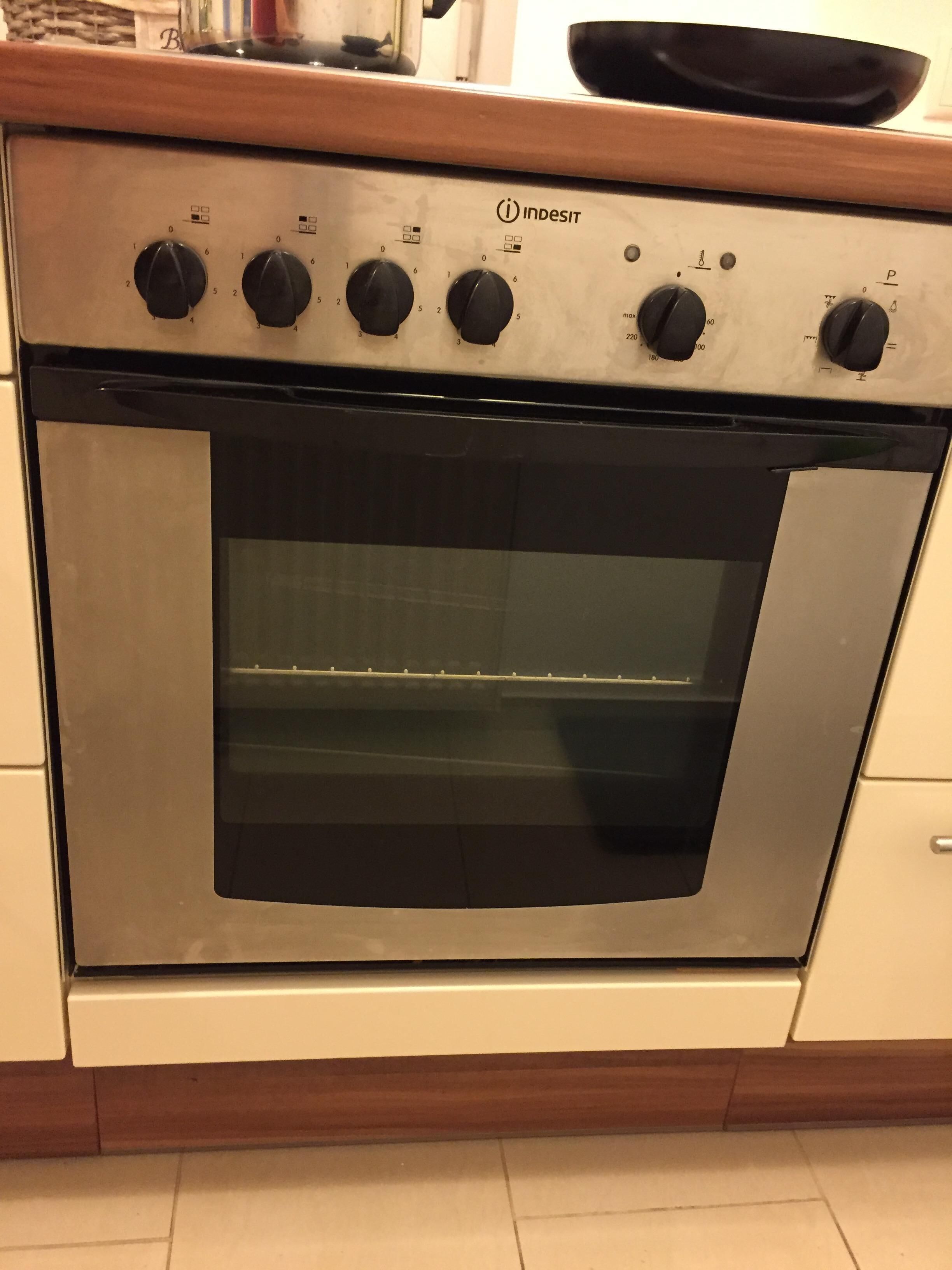 Un horno de acero inoxidable con mandos, una ventana de vidrio y una encimera de madera.