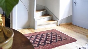Un escalier menant à une porte, un tapis à motifs sur le sol et un luminaire au plafond.
