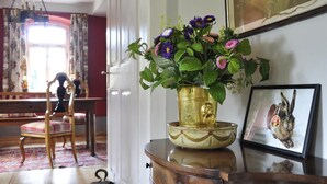 Une pièce comprenant une chaise en bois, une table ornée d’un vase de fleurs et un tableau encadré accroché au mur.