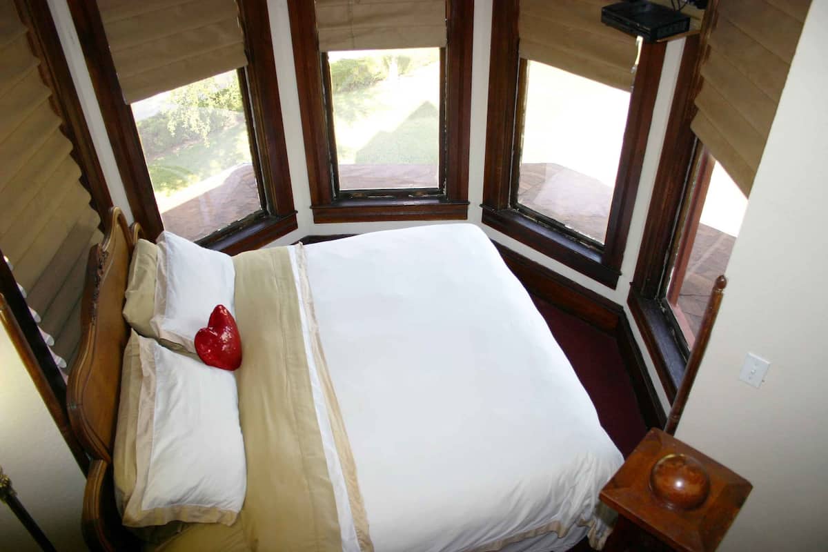 A bedroom with a large bed, a wooden headboard, and a view of the outdoors through a window.