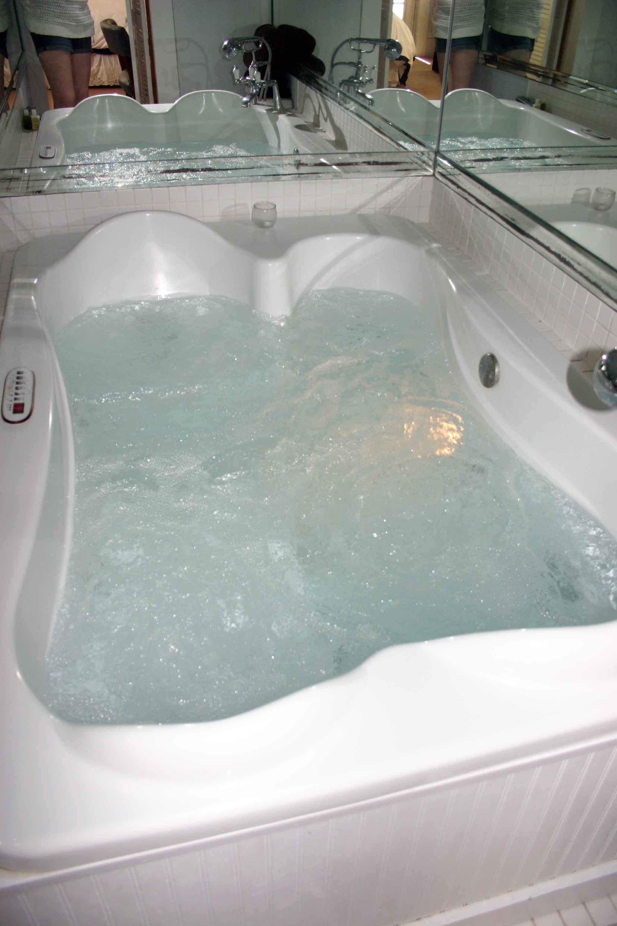 A bathtub with running water, a glass partition, and a control panel.