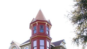A large, two-story house with a prominent tower section and a wrap-around porch.