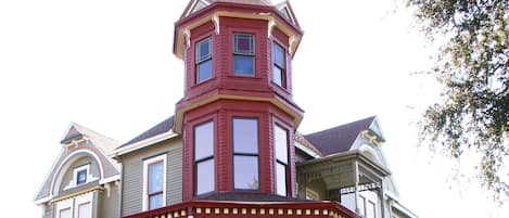 Ein großes, zweistöckiges Haus mit einem markanten Turm und einer umlaufenden Veranda.