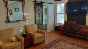 A living room with a large mirror, two armchairs, a sofa, a fireplace, and a TV.