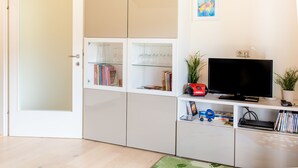 Ein modernes Wohnzimmer mit Fernseher, Bücherregal und einer Tür.