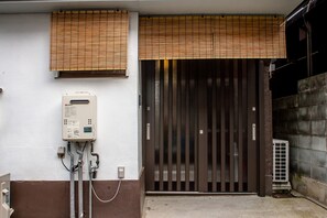 A building entrance with a brown gate, a utility box, and a window with blinds. - Goemon Fushimi (Kyoto)
