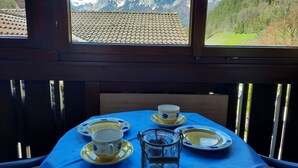 Ein Tisch ist gedeckt mit Tellern, einer Tasse und einer Kerze, mit Blick auf die Berge.