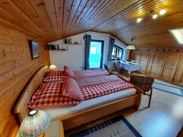 Ein gemütliches Schlafzimmer in einer Holzhütte mit einem Bett, einem Schreibtisch und einem Stuhl.