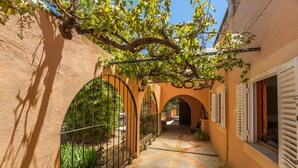 A narrow alleyway with arched doorways, a tiled pathway, and potted plants. - Finca Toni in Alcudia with pool close to the beach (Alcúdia)