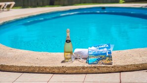 A swimming pool with a bottle of champagne, a glass, and a brochure on the edge. - Finca Toni in Alcudia with pool close to the beach (Alcúdia)
