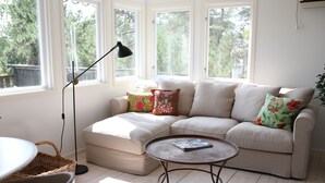 Una sala de estar acogedora con un sofá modular, una mesita redonda y una lámpara de pie.