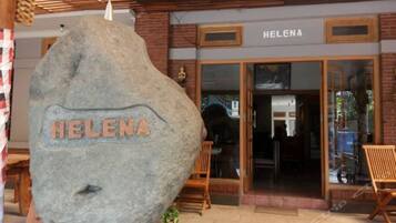 A stone with "HELENA" carved on it in front of a building with a sign reading "HELENA".