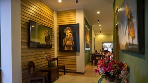 A hallway with wooden paneling, a dining area with chairs and a table, and a vase of flowers. - Helena Guest House (Malang)