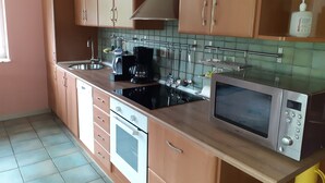 Eine Küche mit Holzausstattung, einem Herd, einem Backofen, einer Mikrowelle und einer Kaffeemaschine.