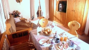 Un coin repas accueillant, avec une table dressée pour le petit-déjeuner, des meubles en bois et une vue sur la Tour Eiffel par la fenêtre.