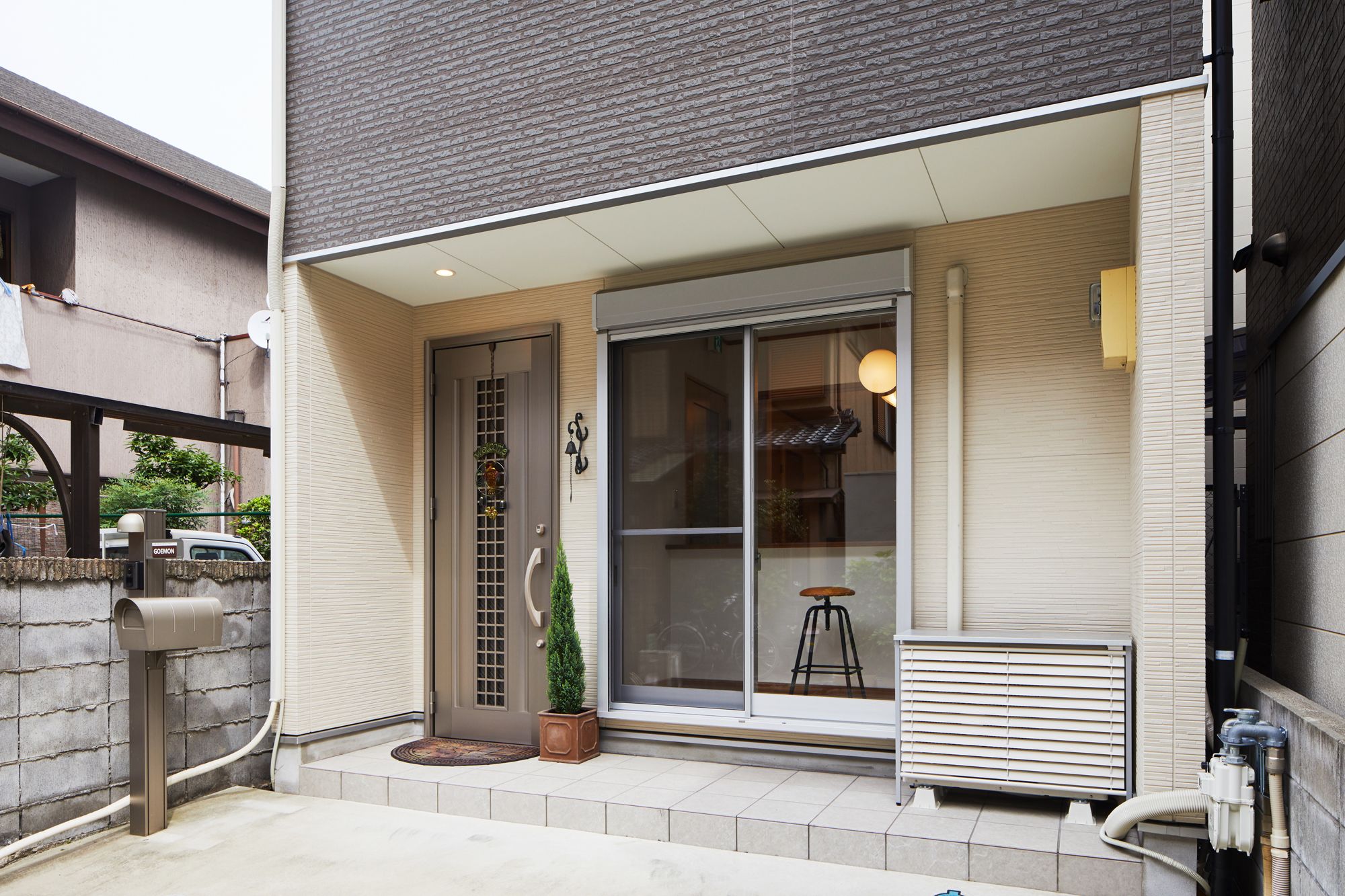 A modern building with a large glass door, a small potted plant, and a metal bench outside.