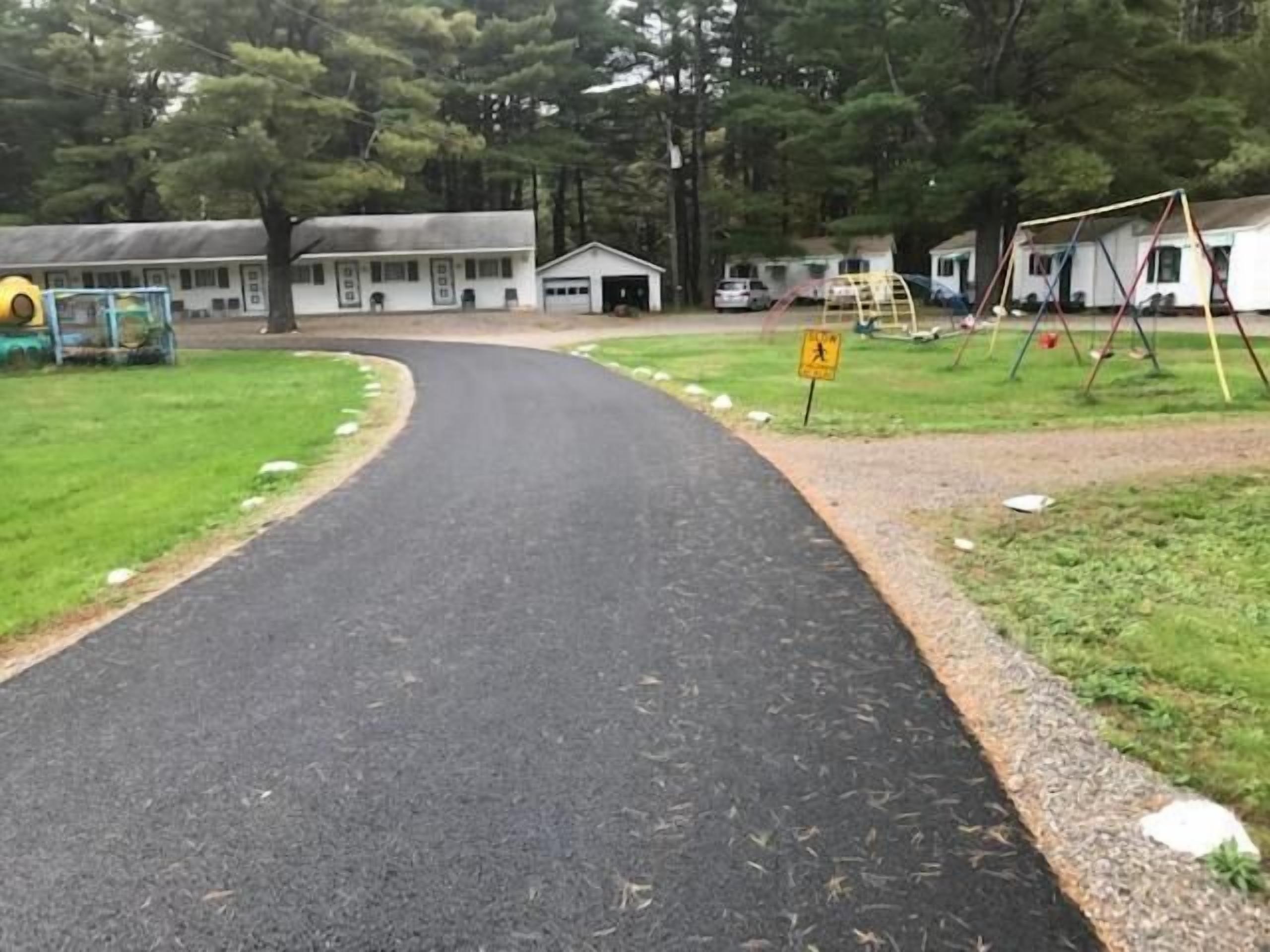 A road curving through a residential area with houses and a playground.