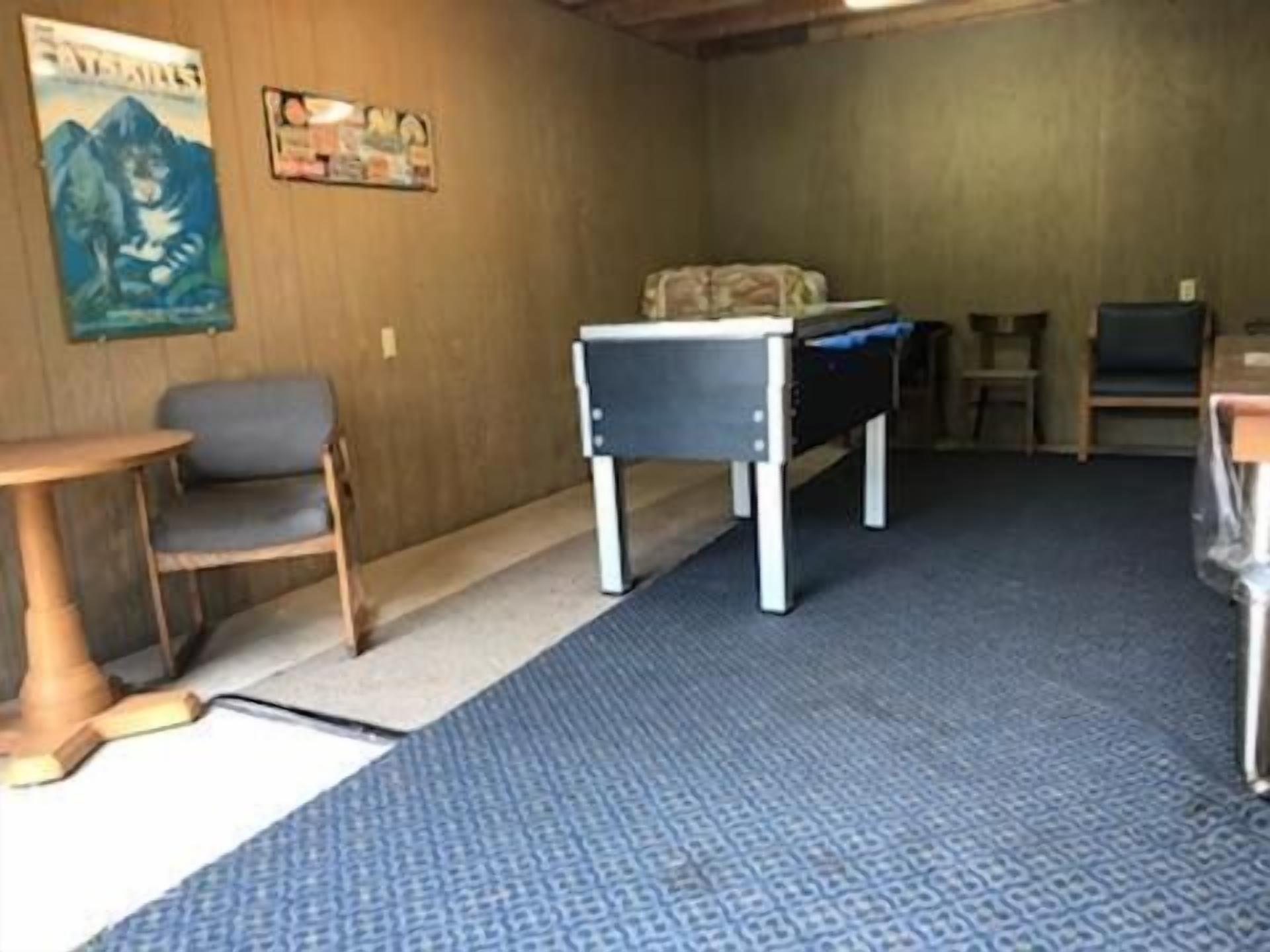 Una habitación con alfombra azul, una pequeña mesa, una silla y una cama con cubrecama azul.