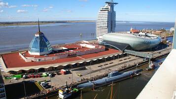 A waterfront area with a distinctive blue and white building, a large cruise ship docked, and a tall skyscraper in the background.