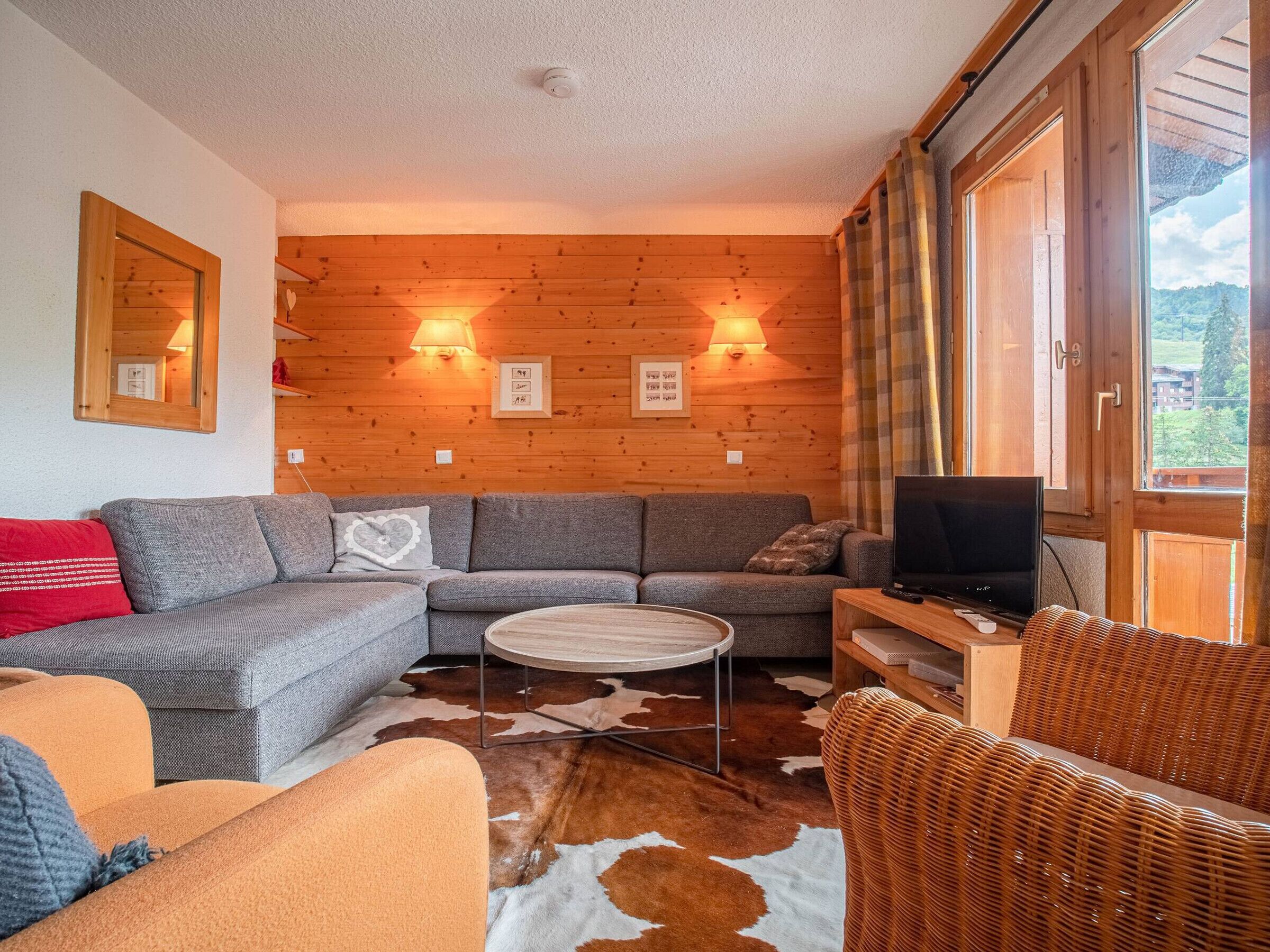 Un salon chaleureux avec un mur en bois, un canapé, une table basse et un fauteuil en osier.