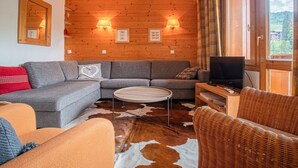 Un salon chaleureux avec un mur en bois, un canapé, une table basse et un fauteuil en osier.