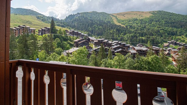 Vue d’une station de montagne avec des bâtiments de style chalet, une balustrade en bois et un ciel dégagé.