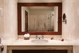 A bathroom with a large mirror, a sink, and a shower.