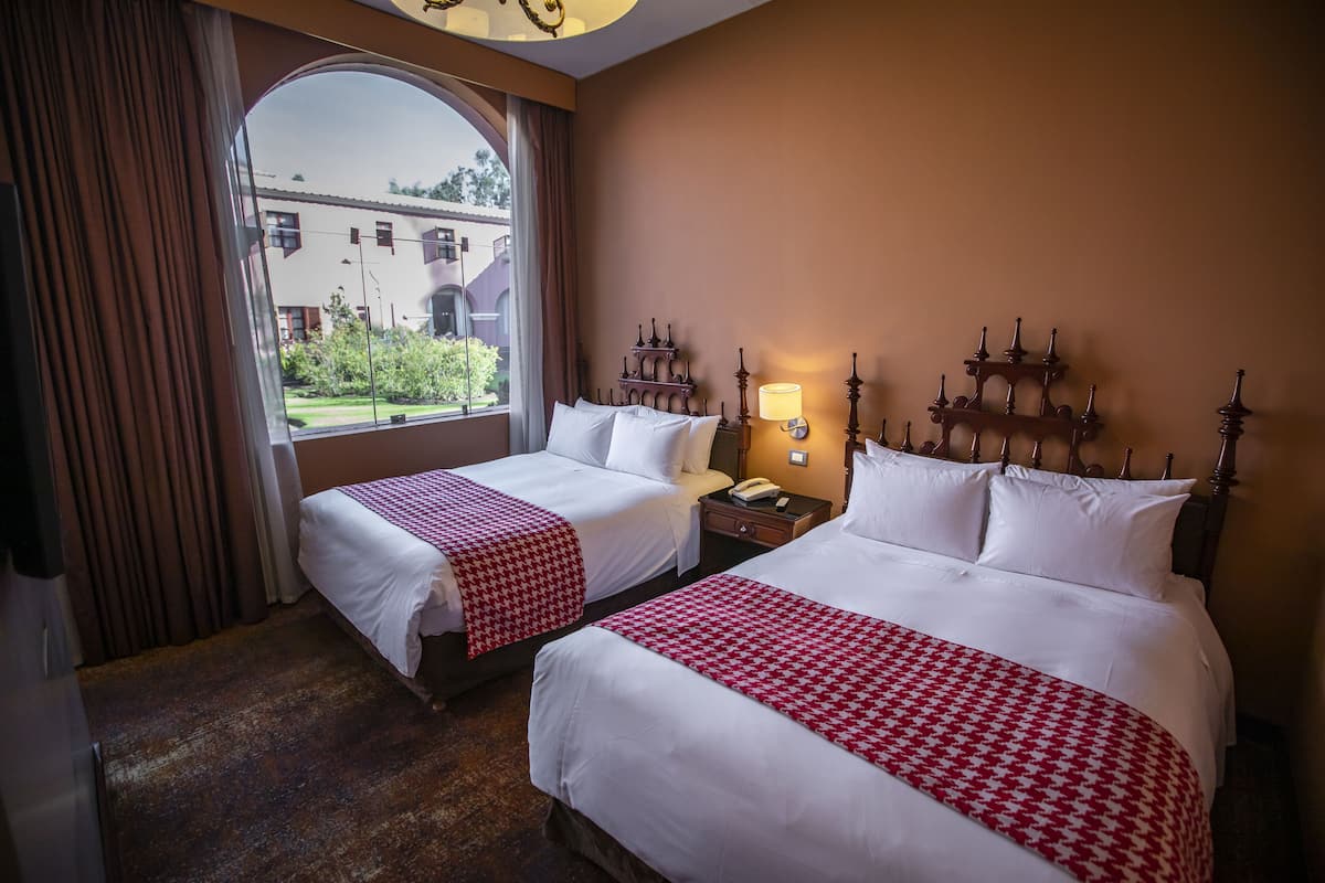 Une chambre d’hôtel avec deux lits, une grande fenêtre et une vue sur les bâtiments environnants.