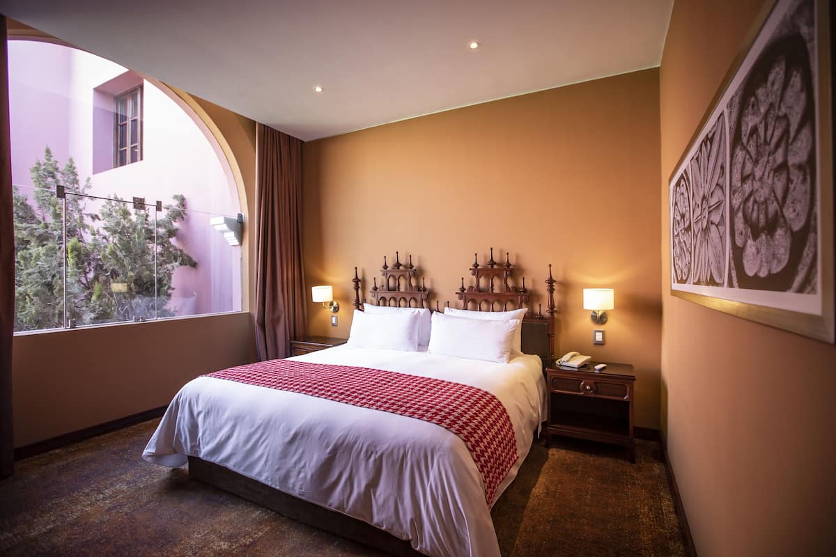 Une chambre d’hôtel avec un grand lit, deux tables de chevet, une fenêtre avec vue et un élément décoratif mural.