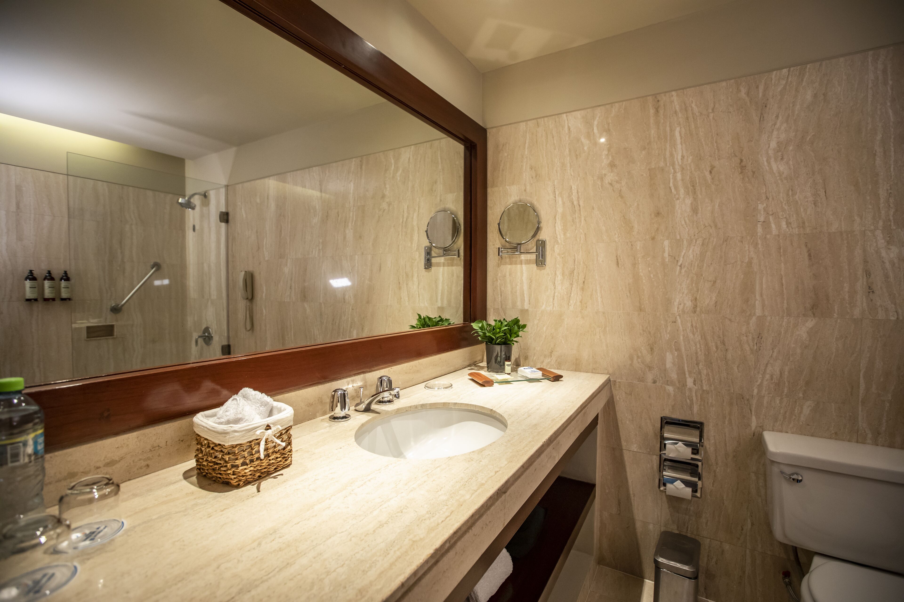 Un baño moderno con un espejo grande, un lavamanos y un inodoro.