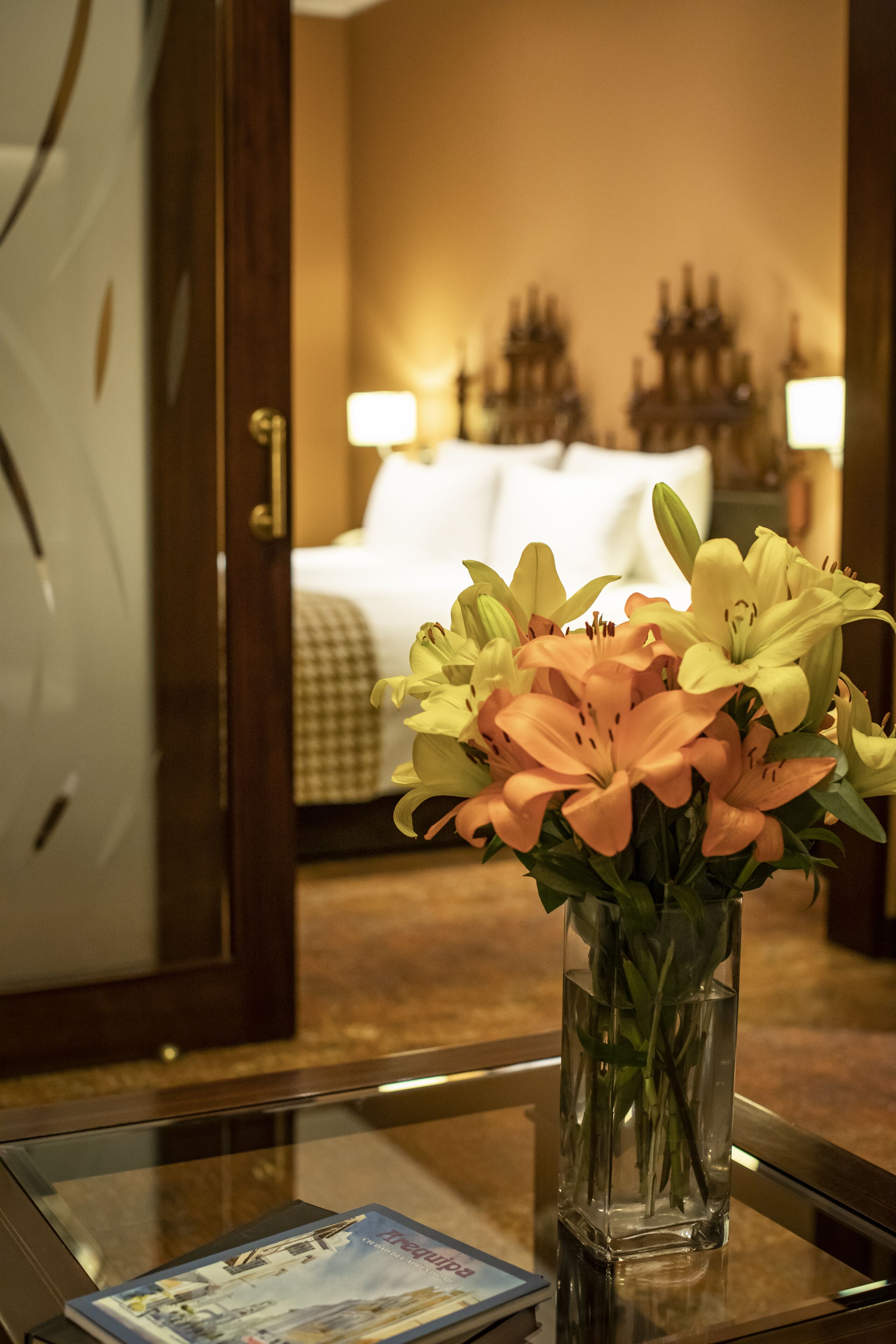 Una habitación de hotel con una cama, un florero sobre una mesa y una lámpara.