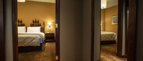 Habitación de hotel con una cama grande, mesita de noche, lámpara y un espejo que refleja la habitación.