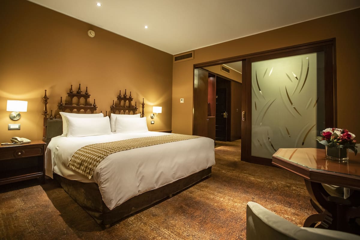 Une chambre d’hôtel avec un grand lit, des lampes de chevet, un bureau avec une chaise et un miroir.