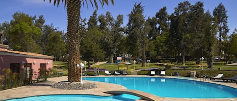 Una piscina al aire libre, sombrillas, tumbonas