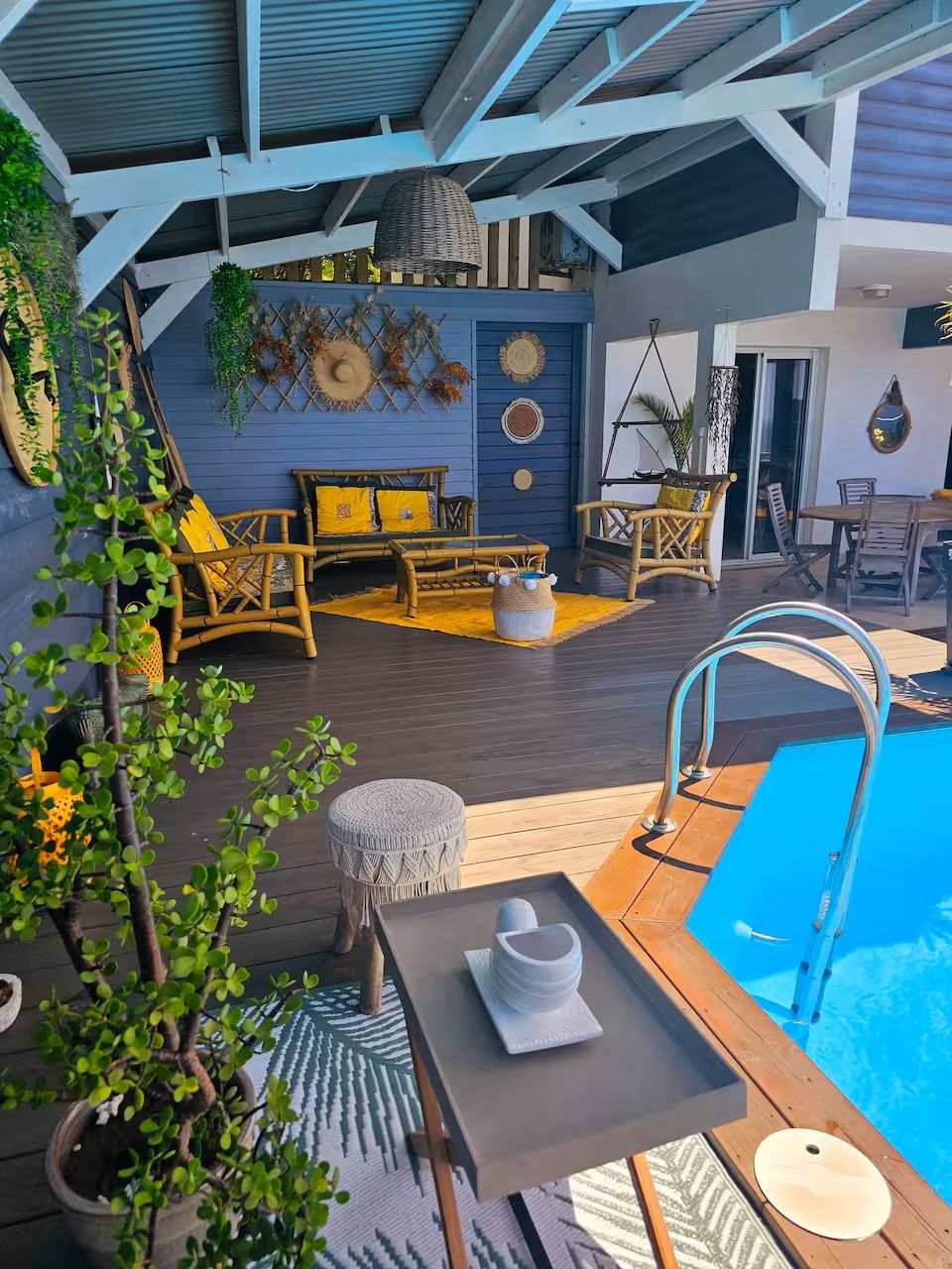 An outdoor pool area with a wooden deck, lounge chairs, and a small table with a tray.