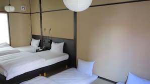 A hotel room with three beds arranged in a row, a ceiling fan, and a paper lantern. - Kyoto Oyado ZEN (Kyoto)