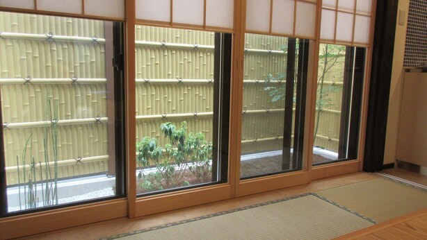 A traditional Japanese room with tatami flooring, sliding shoji doors, and a view of a bamboo fence and greenery outside. - Kyoto Oyado ZEN (Kyoto)