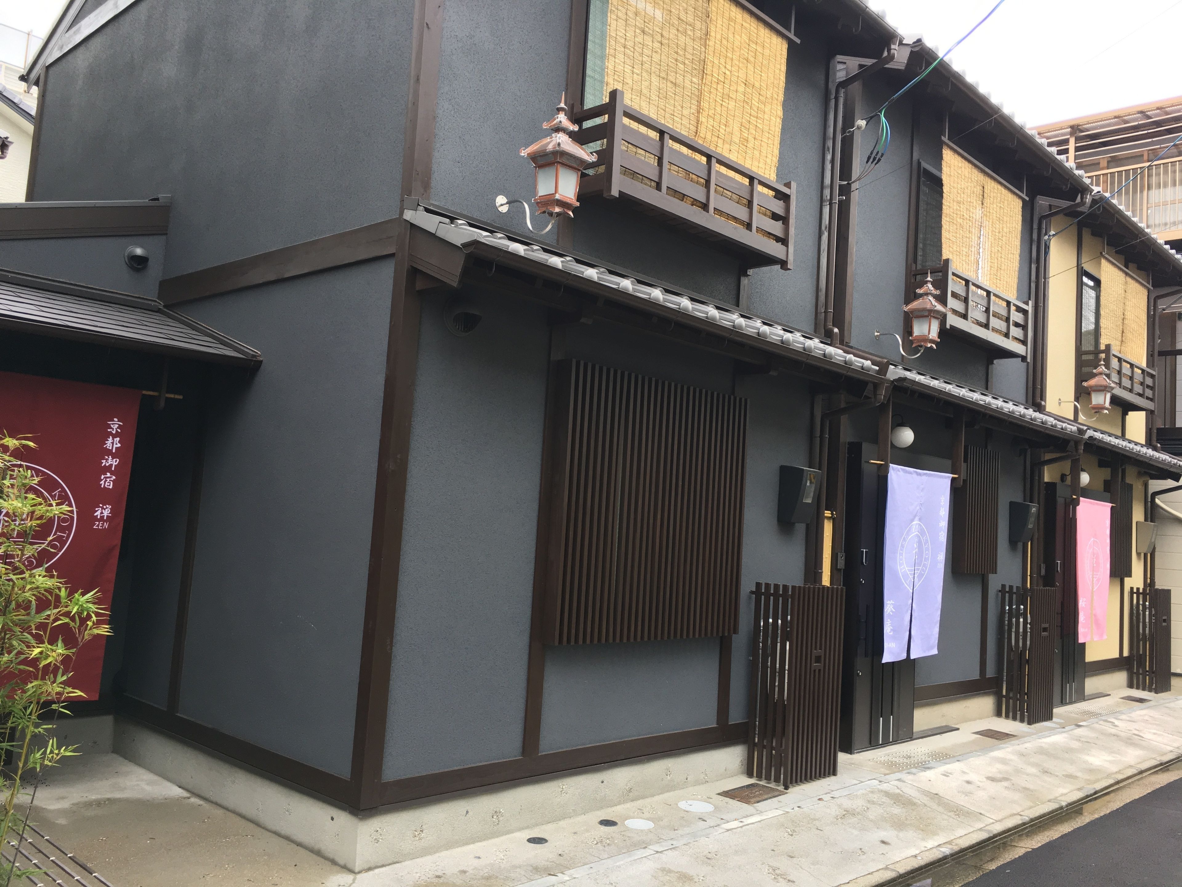 A traditional Japanese building with a dark facade, wooden shoji screens, and a small balcony.