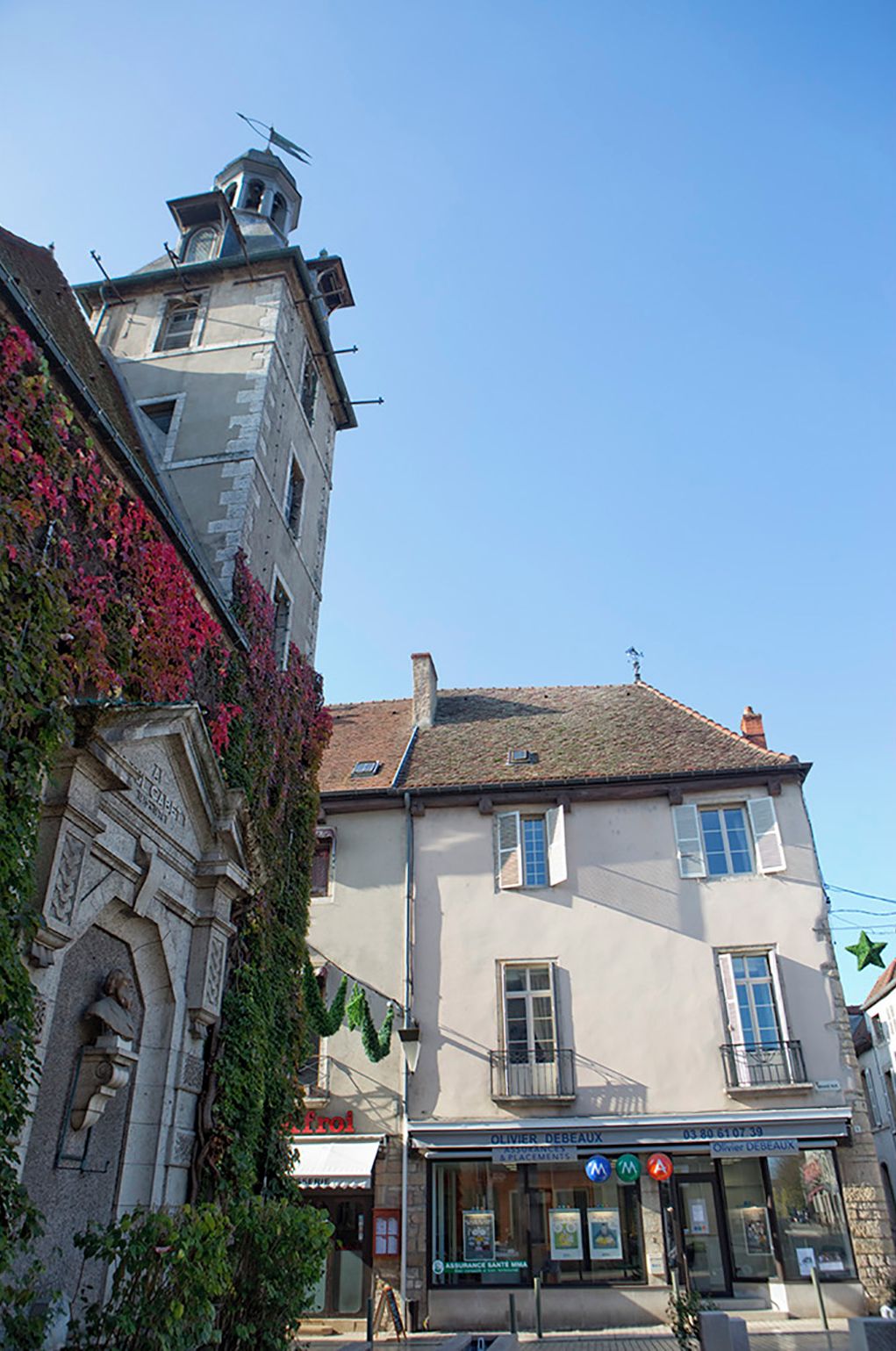 Ein Gebäude mit einem Uhrturm, einem Geschäft im Erdgeschoss und einem strahlend blauen Himmel.