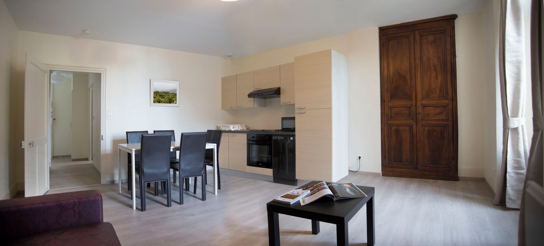 Ein modernes Wohnzimmer mit Essbereich, einer Küche und einem großen, hölzernen Kleiderschrank.