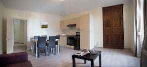 Ein modernes Wohnzimmer mit Essbereich, einer Küche und einem großen, hölzernen Kleiderschrank.