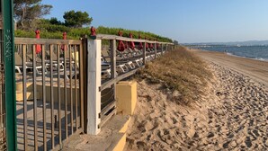 Une zone de plage agrémentée d’une clôture en bois, de parasols rouges et de chaises longues.