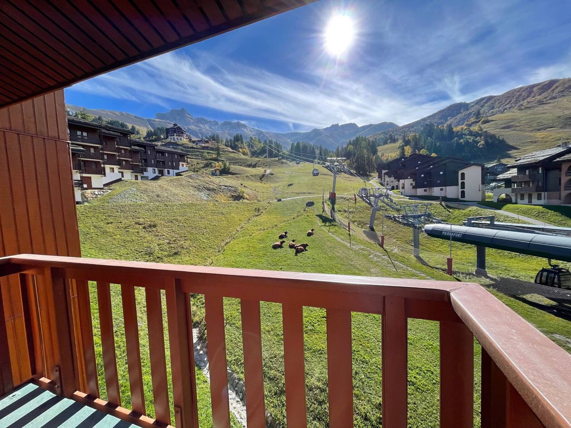 Ein Balkon mit Blick auf eine Berglandschaft, eine Seilbahn und mehrere Gebäude.