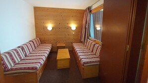 Une pièce de taille modeste, avec deux bancs en bois, une petite table et un miroir sur le mur de droite.