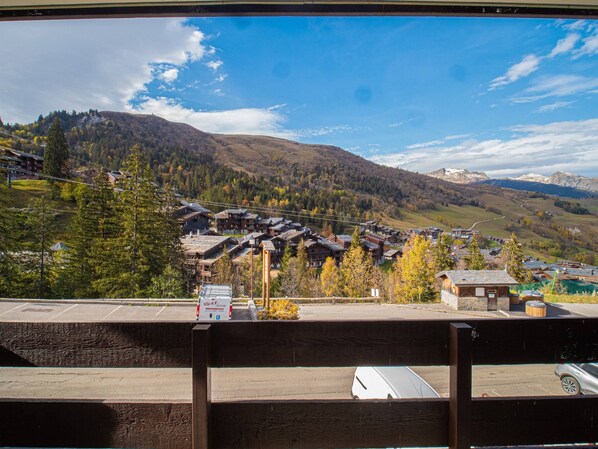 A mountainous landscape with a cluster of buildings, likely a resort or lodge, with a clear sky above.