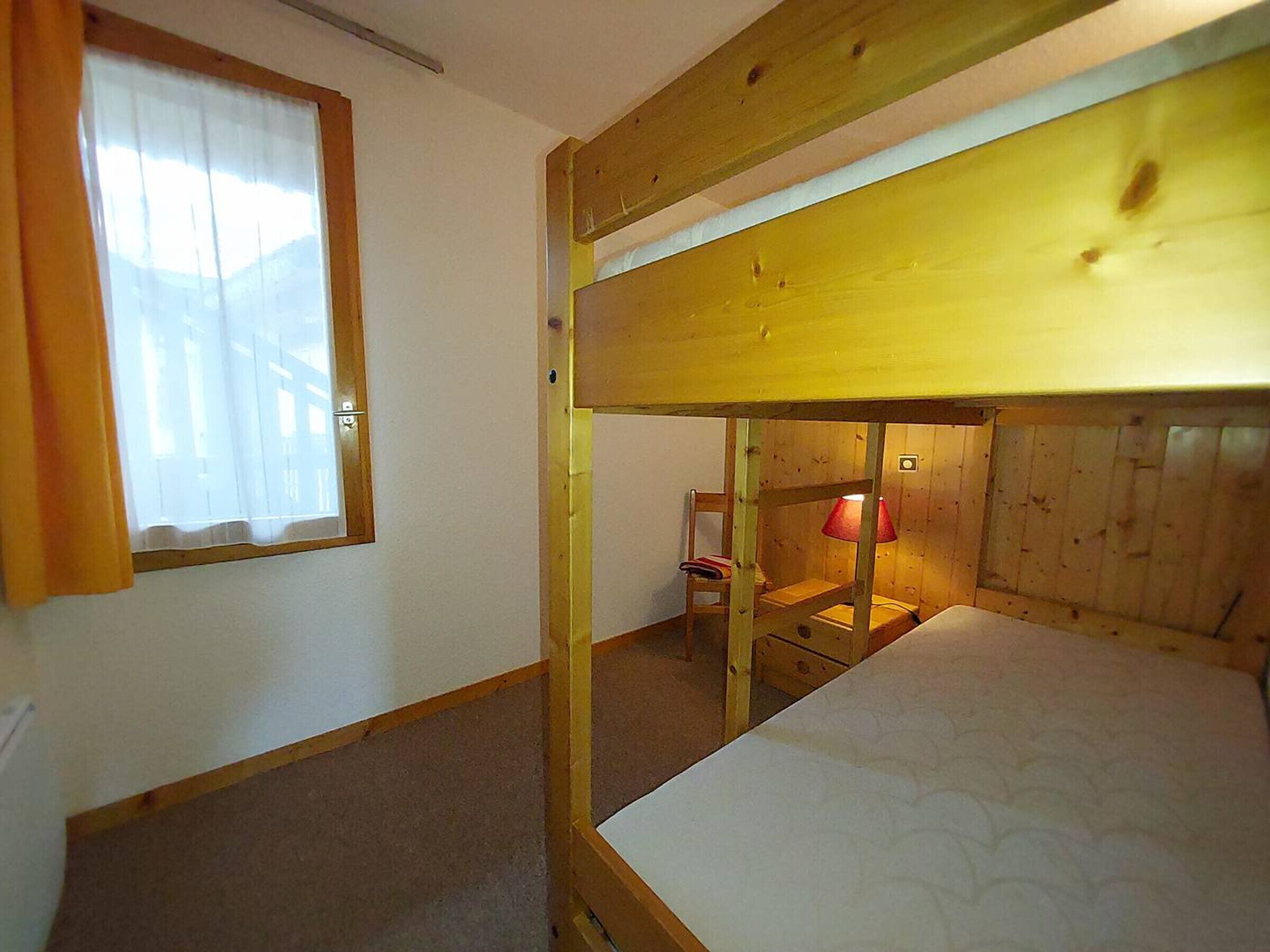 Ein Schlafraum mit Etagenbetten, einem Fenster und einem Sessel.