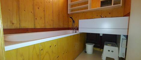 A small, compact bathroom with wooden walls, a white sink, and a mirror above it.