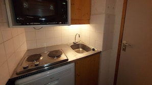 A compact kitchen with a microwave, stove, and sink.